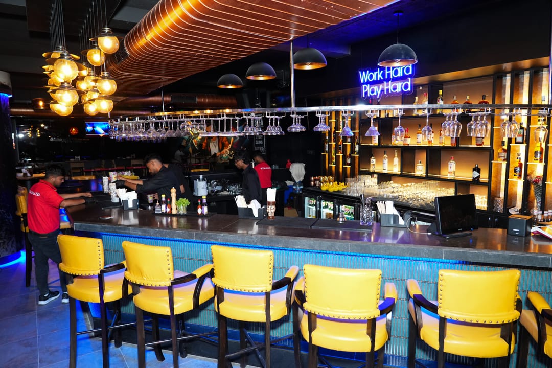 Bartenders preparing drinks under Work Hard Play Hard signage